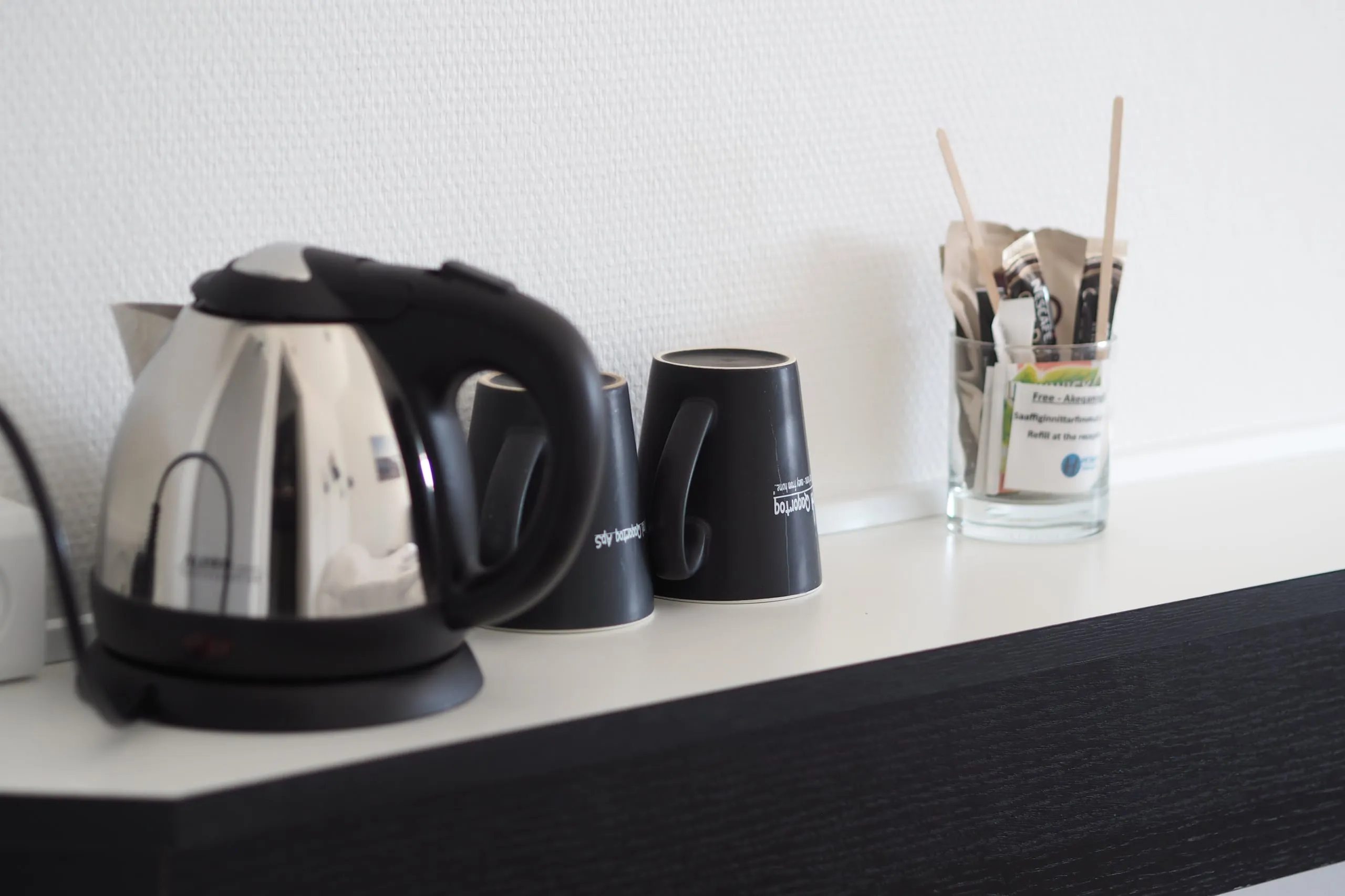 The welcome tray: a kettle, two mugs and a glass of sachets and stirrers.